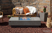 Load image into Gallery viewer, elementi plus monte carlo fire pit table on a beautiful patio with wind guard and flame.