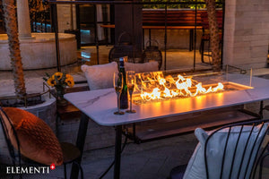 Elementi Plus Oslo outdoor dining table  with flame in an evening setting