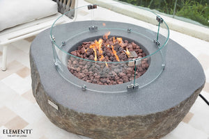 elementi Plus Boulder Fire Table with flame and wind guard in an outdoor setting