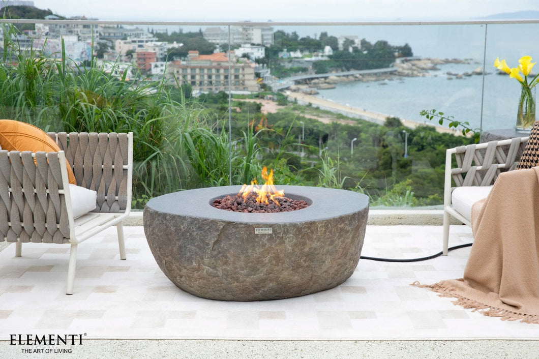 Elementi Boulder fire table with a flame on a patio