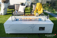Load image into Gallery viewer, elementi plus carrara fire table with flame and blue glass in a patio setting