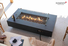 Load image into Gallery viewer, elementi positano fire table with flame and wind guard on a covered patio