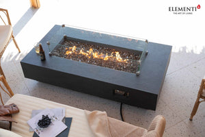 elementi positano fire table with flame and wind guard on a covered patio